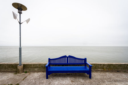 Lonely blue bench on a concrete pier under a cloudy sky in Nida Lithuaniaの写真素材