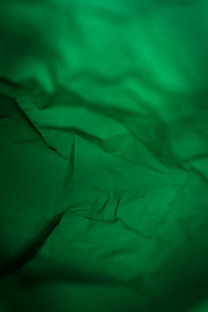 Extreme close up of green empty plastic bag background. The plastic surface is wrinkly and tattered...