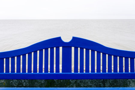 Part of lonely blue bench on a concrete pier under a cloudy sky in Nida Lithuaniaの写真素材