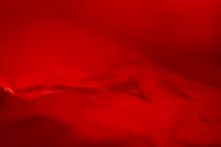 Extreme close up of red empty plastic bag background. The plastic surface is wrinkly and tattered making abstract pattern. Selective focus, shallow depth of field.の写真素材