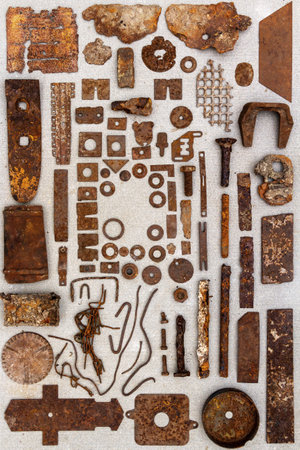 A group of various old rusty bits and pieces arranged on a concrete surface. Old rusty nuts, bolts,...
