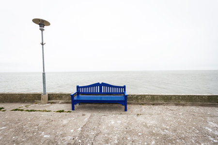 Lonely blue bench on a concrete pier under a cloudy sky in Nida Lithuaniaの写真素材
