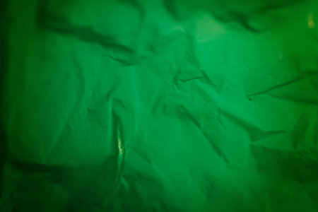 Extreme close up of green empty plastic bag background. The plastic surface is wrinkly and tattered making abstract pattern. Selective focus, shallow depth of field.の写真素材