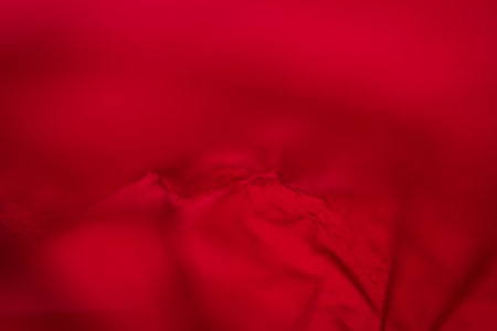Extreme close up of red empty plastic bag background. The plastic surface is wrinkly and tattered making abstract pattern. Selective focus, shallow depth of field.の写真素材
