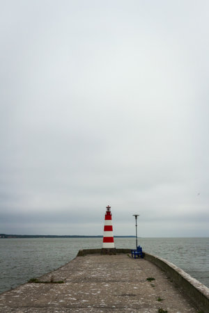 Lighthouse on a concrete pier under a cloudy sky in Nida, Curonian Spit and Curonian Lagoon,...