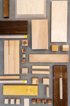 A group of various wooden pieces arranged on a concrete surface. Wooden planks, sticks, and blocks are laid out on a gray background.の写真素材
