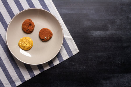 Bowl with some cookies and blue striped table cloth on black chalkboard texture. Flat lay. Top view. Food concept.の写真素材
