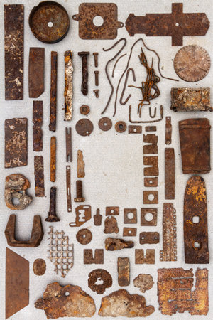 A group of various old rusty bits and pieces arranged on a concrete surface. Old rusty nuts, bolts, nails and other parts flay lay on gray background.の写真素材