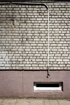 White brick wall with some cables and basement window. Architectural detail.の写真素材