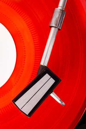 Close up of turntable needle on a record. Turntable playing vinyl. Needle on rotating red disk.
