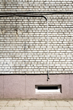 White brick wall with some cables and basement window. Architectural detail.の写真素材