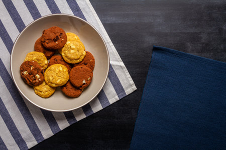 Bowl with some cookies and blue striped table cloth on black chalkboard texture. Flat lay. Top view. Food concept.の写真素材