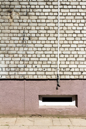 White brick wall with some cables and basement window. Architectural detail.の写真素材