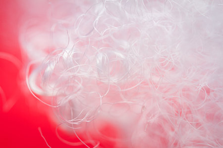 Extreme macro of polyester stable fiber on red background. Selective focus, shallow depth of field. Abstract dreamy backgroundの写真素材