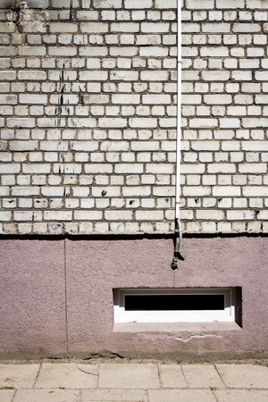 White brick wall with some cables and basement window. Architectural detail.