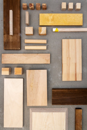 Flat lay of various wood and plywood pieces on concrete texture. Carpentry background.