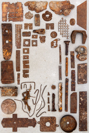A group of various old rusty bits and pieces arranged on a concrete surface. Old rusty nuts, bolts, nails and other parts flay lay on gray background.の写真素材
