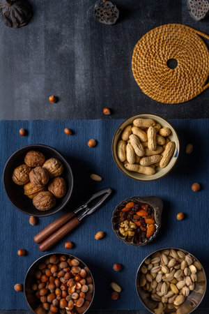 Bowls with nuts and blue table cloth on black chalkboard background. Flat lay. Top view.の写真素材