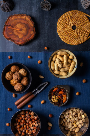 Bowls with nuts and blue table cloth on black chalkboard background. Flat lay. Top view.