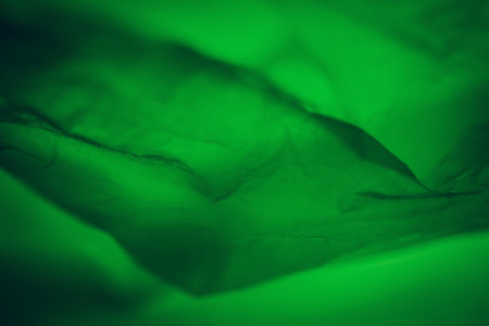 Extreme close up of green empty plastic bag background. The plastic surface is wrinkly and tattered making abstract pattern. Selective focus, shallow depth of field.の写真素材