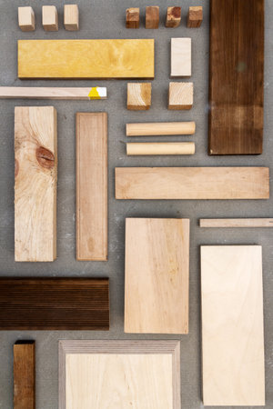 Flat lay of various wood and plywood pieces on concrete texture. Carpentry background.