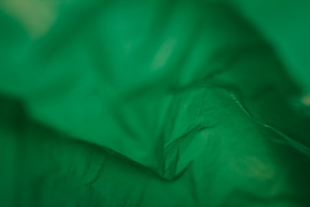 Extreme close up of green empty plastic bag background. The plastic surface is wrinkly and tattered making abstract pattern. Selective focus, shallow depth of field.の写真素材