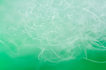 Extreme macro of polyester stable fiber on green background. Selective focus, shallow depth of field. Abstract dreamy backgroundの写真素材