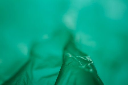 Extreme close up of green empty plastic bag background. The plastic surface is wrinkly and tattered making abstract pattern. Selective focus, shallow depth of field.の写真素材