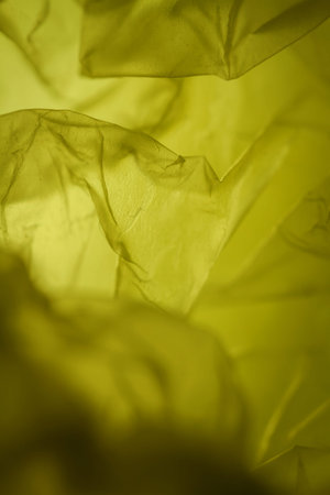 Extreme close up of yellow empty plastic bag background. The plastic surface is wrinkly and tattered...