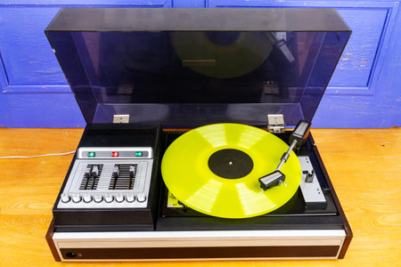 Vintage turntable vinyl record player with yellow vinyl on a table