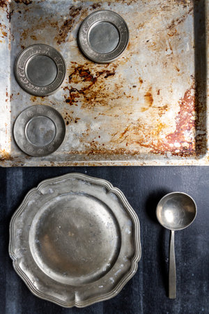 Old metal kitchen utensils on black chalkboard background. Food themed flat lay.