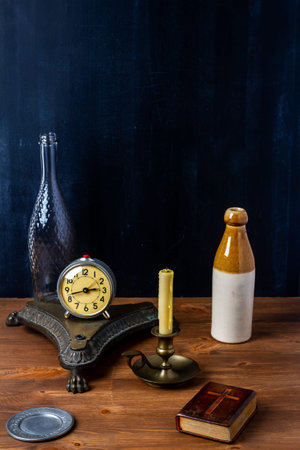 Various old vintage objects on brown wooden table by the black wall.