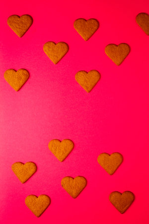 Top view of heart shaped cookies on a vibrant pink background. Dessert photography, sweet treats.