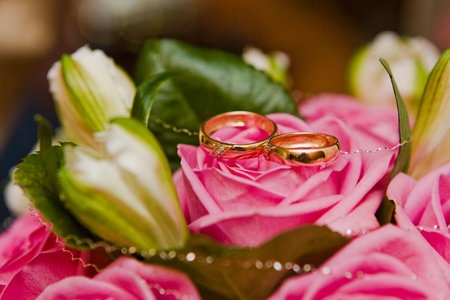 Gold wedding rings on a bouquet of pink rosesの写真素材