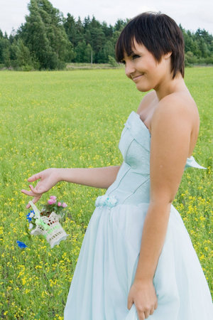 happy young woman in wedding dress on field in summerの写真素材