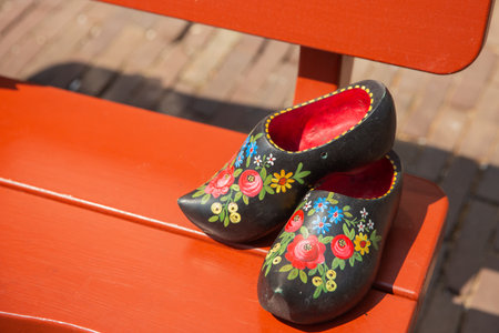 Traditional Dutch wooden shoes on a bench in the park. Selective focus.