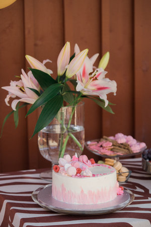 Cake on the table with lily flowers and macaroonsの写真素材
