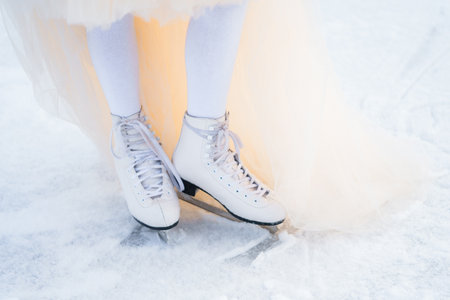 feet of a girl in white ice skates on the ice rinkの写真素材