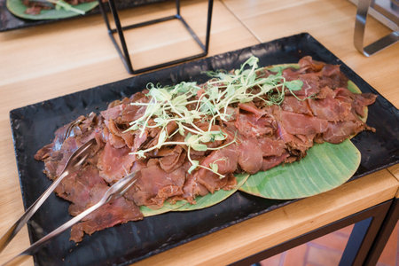 Sliced beef on a black plate in a restaurantの写真素材
