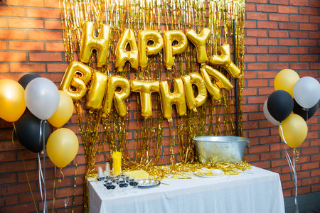 Happy Birthday party decoration with golden folio balloons and lamee on brick wall backgroundの写真素材