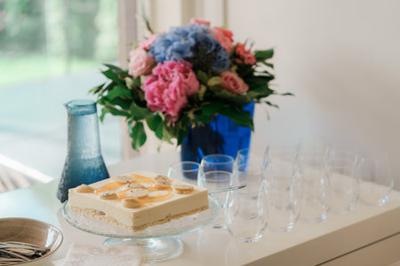 cheese cake on the table with flowers in a blue vase.の写真素材