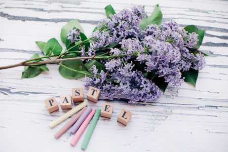 Purple lilac flowers on a white wooden background with wooden lettersの写真素材