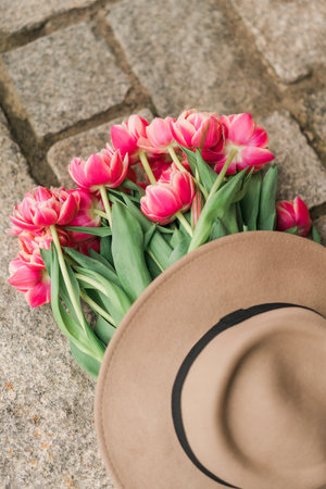 Hat and bouquet of pink tulips on the stone pavement.の写真素材