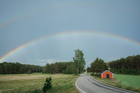 Double rainbow over the road in the meadow in the summer.の写真素材