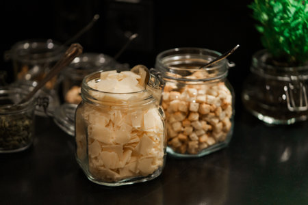 Close up of glass jars with pieces of parmesan cheese and croutons on dark backgroundの写真素材