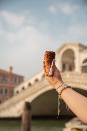 Woman hand holding ice cream in front of the Rialto Bridge in Venice, Italyの写真素材
