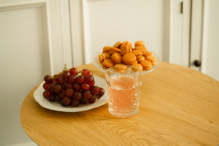 A glass of limonade with cookies and grapes on a wooden table.の写真素材