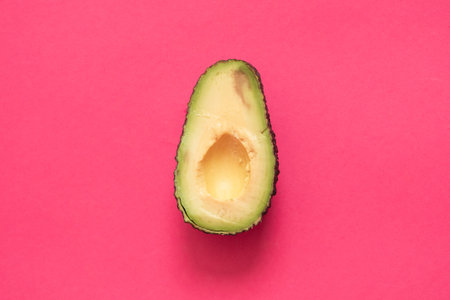 Avocado cut in half on a pink background. Top view.の写真素材