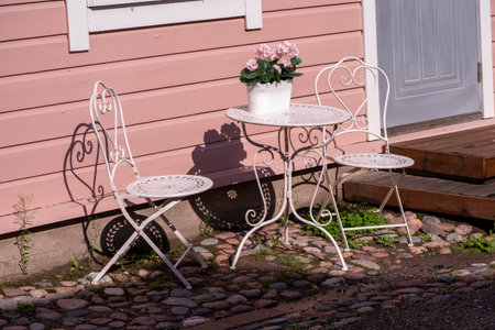 White metal table and chairs in front of a pink wooden house.の写真素材