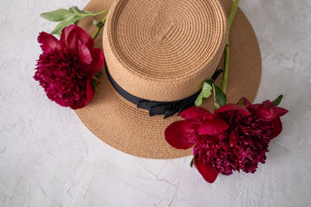 Straw hat with red peony flowers on a white background.の写真素材
